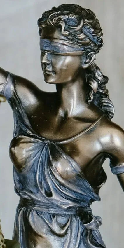 Bronze statue of a blindfolded woman with wavy hair and draped clothing.